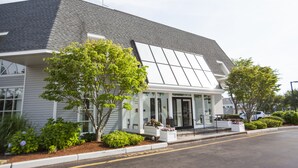 Un bâtiment moderne doté d’un toit en pente, de grandes fenêtres et d’un espace d’entrée abrité avec des sièges.