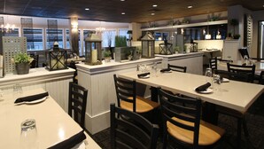 L’intérieur d’un restaurant, avec ses tables et ses chaises, ses lanternes décoratives et ses plantes en pot.
