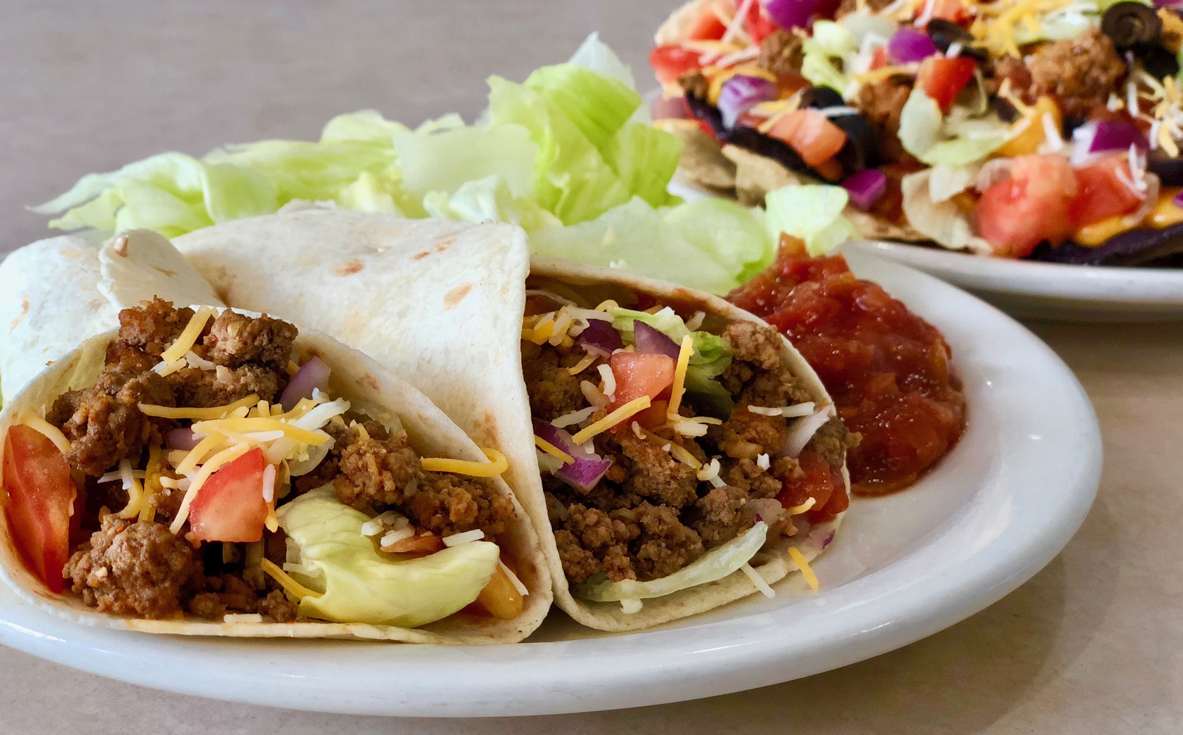 A plate with two tacos and a side salad.