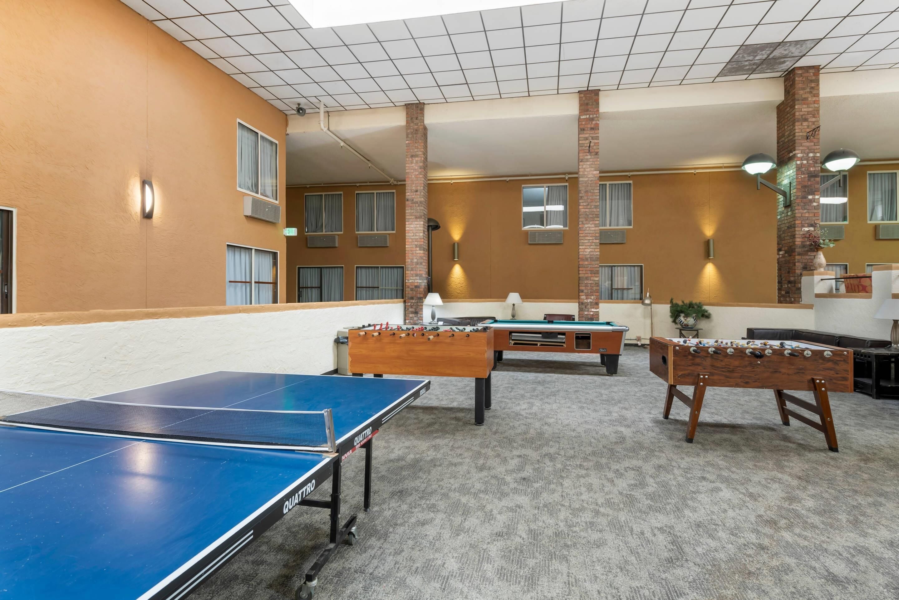 Een kamer met een tafeltennistafel, een tafelvoetbaltafel en een biljarttafel.