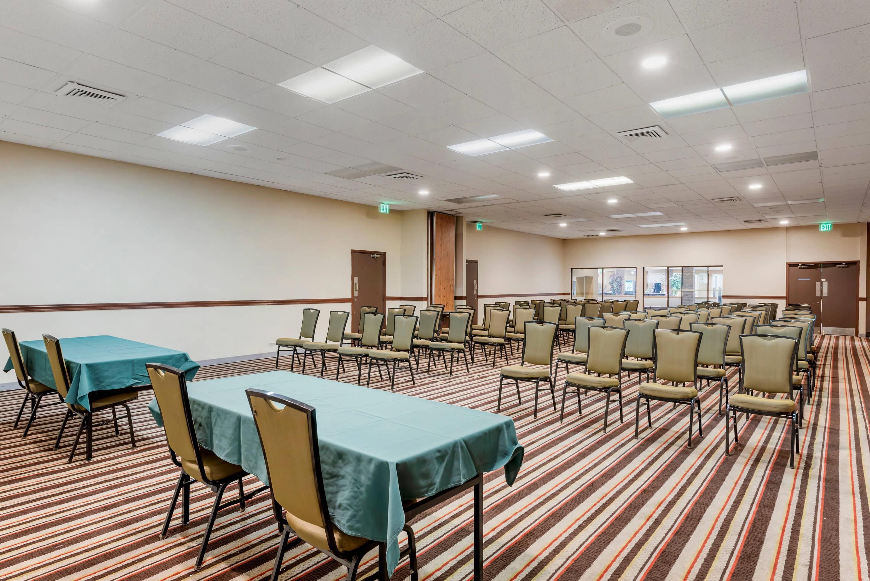 A conference room with tables and chairs, carpeted floor, and ceiling lights.