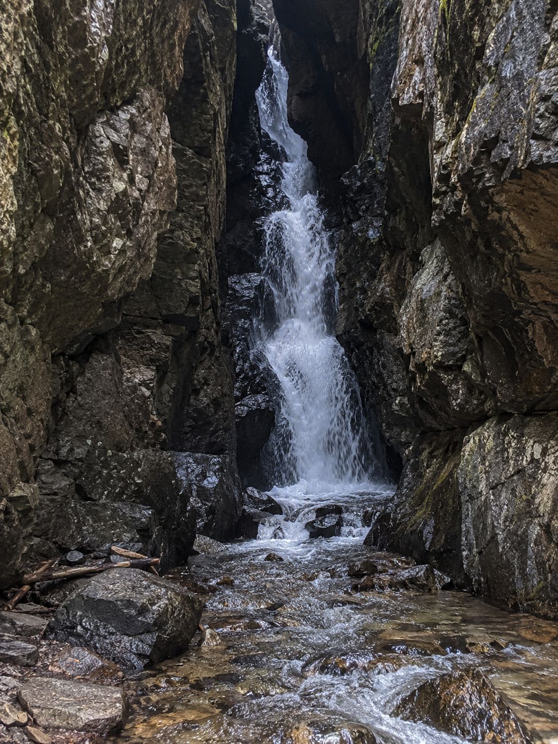 Una cascada en un desfiladero rocoso con agua fluyendo sobre las rocas.