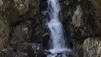 Una cascada en un desfiladero rocoso con agua fluyendo sobre las rocas.