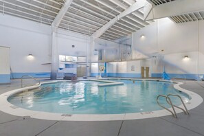 An indoor swimming pool with clear lanes, a diving board, and a lifeguard chair.