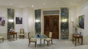 A spacious lobby with a chess table, comfortable seating, and a grand wooden door. - Apartmenthotel Kaiser Karl (  Self-check-in )  (Bonn)