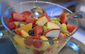 A clear glass bowl filled with a variety of fresh fruits including strawberries, blueberries, kiwi, pineapple, and watermelon. - Apartmenthotel Kaiser Karl (  Self-check-in )  (Bonn)