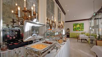 Ein Bereich mit Buffet und verschiedenen Speisen, eine Kaffeemaschine sowie eine grüne Couch im Hintergrund.