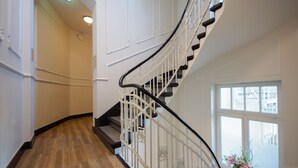 A curved staircase with white railings and wooden steps, leading to a landing with a window. - Apartmenthotel Kaiser Karl (  Self-check-in )  (Bonn)