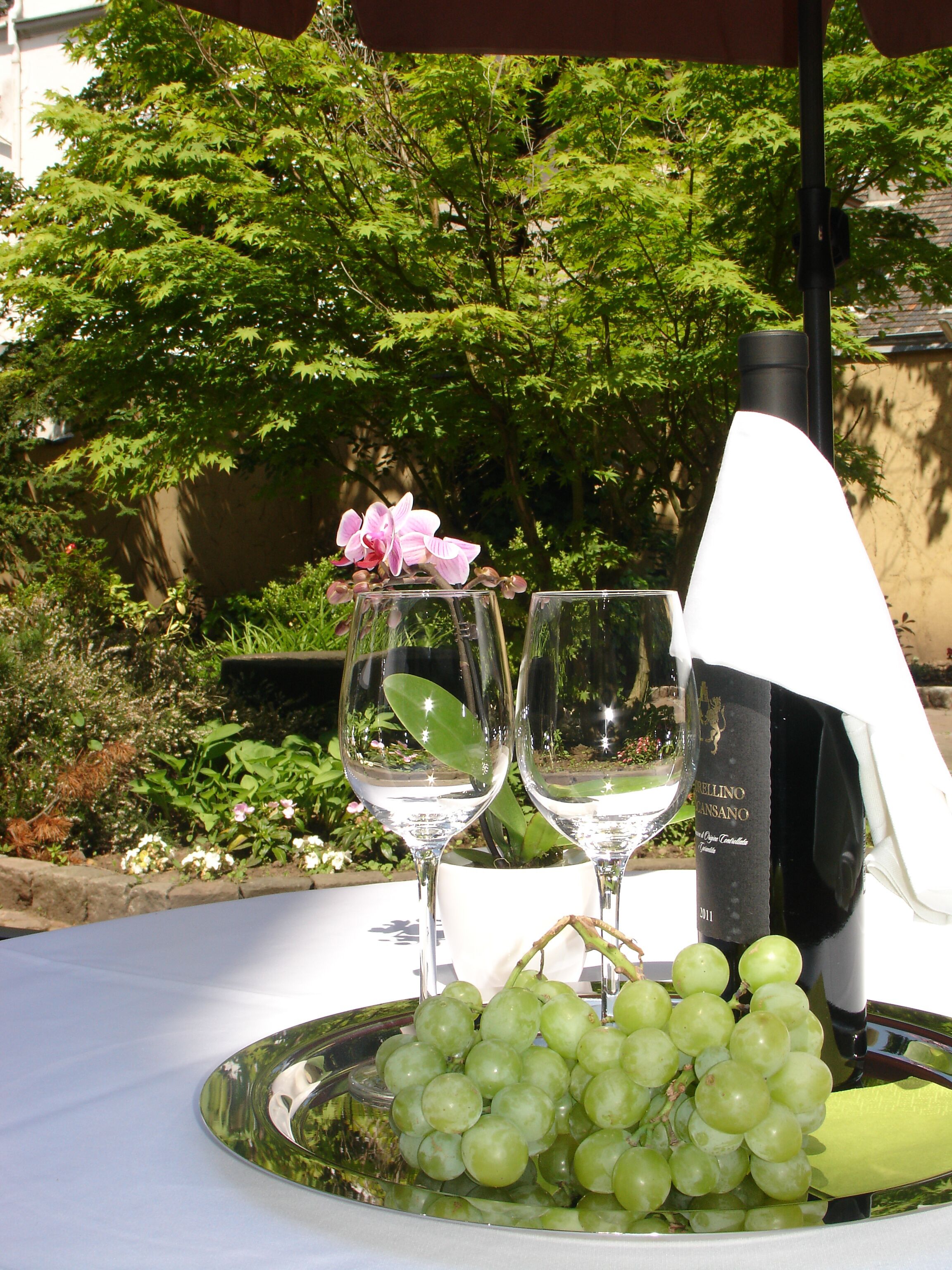 A table with two wine glasses, a bottle of wine, and a plate of grapes.