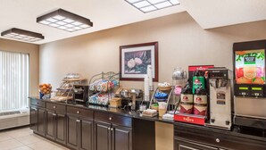 A breakfast bar with various food items, a coffee machine, and a juice dispenser. - Days Inn by Wyndham Westminster (Westminster)