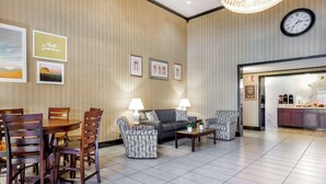 A hotel lobby with a dining area, sofas, and a kitchen visible through an open door. - Days Inn by Wyndham Westminster (Westminster)
