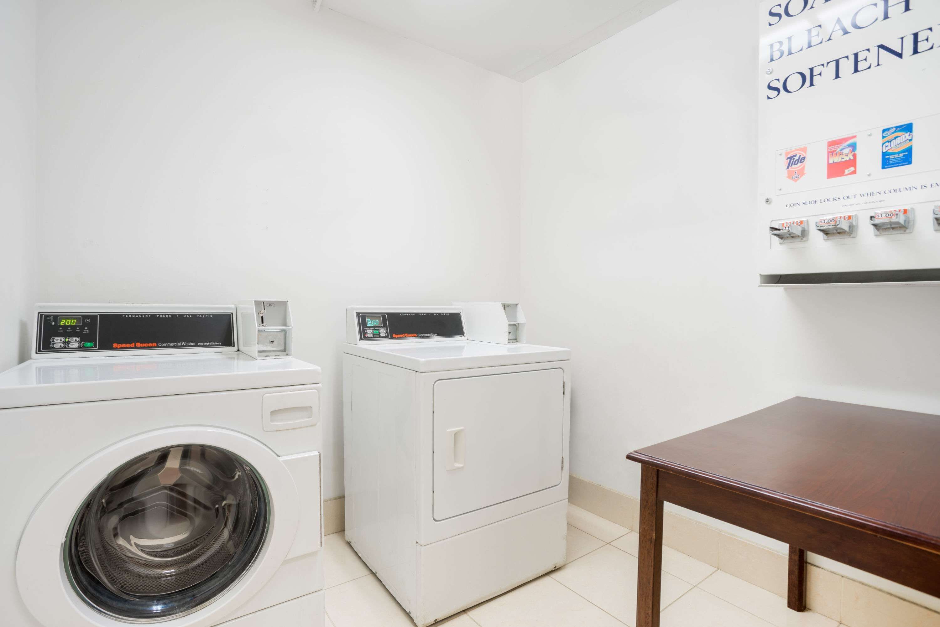 A laundry area with two washing machines and a coin-operated dryer.
