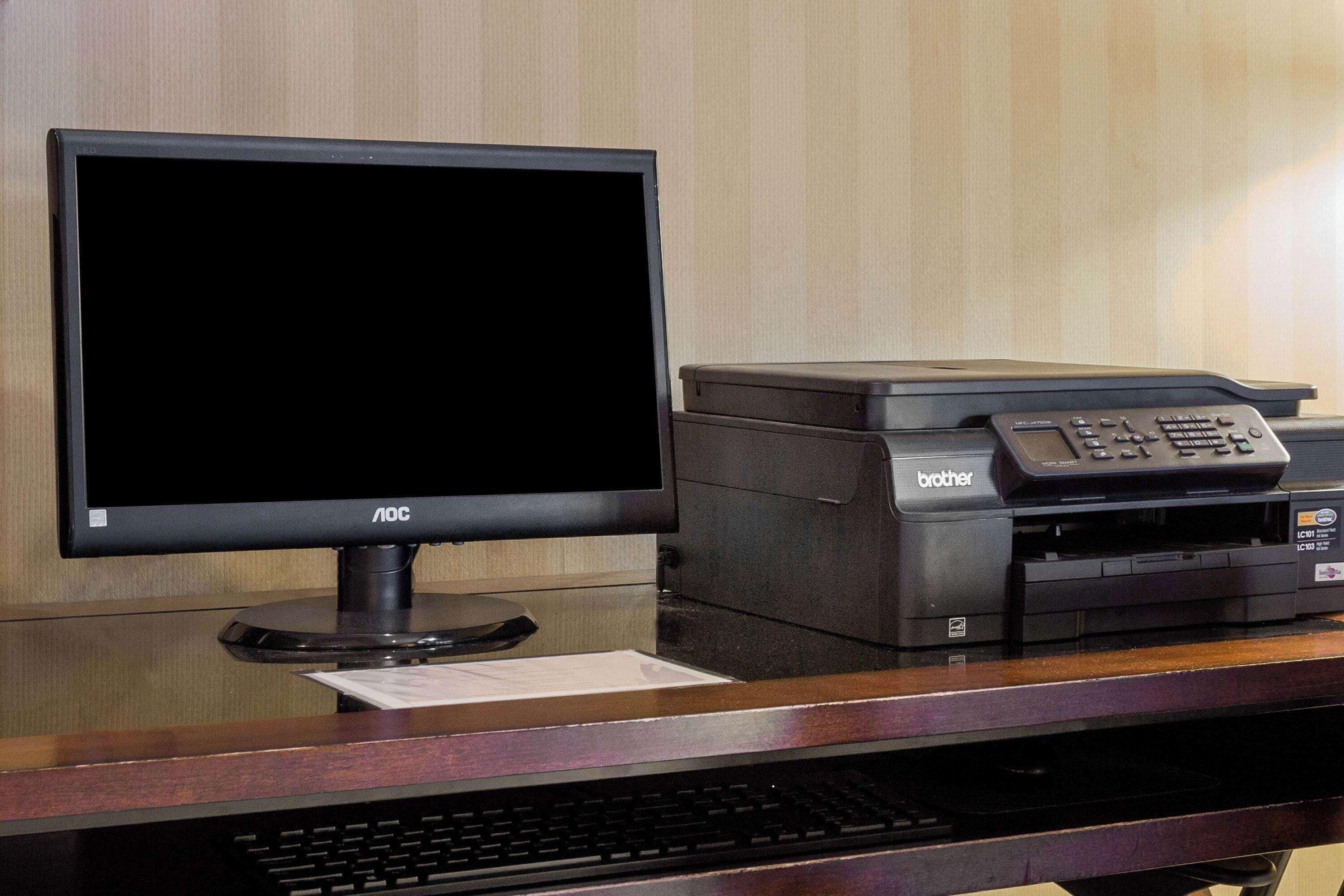 A reception desk with a flat-screen monitor, a Brother printer, and a keyboard.