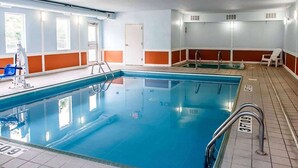 Une piscine intérieure avec des lignes de démarcation bien visibles, un poste de surveillance pour le sauveteur et une porte à l’arrière-plan.