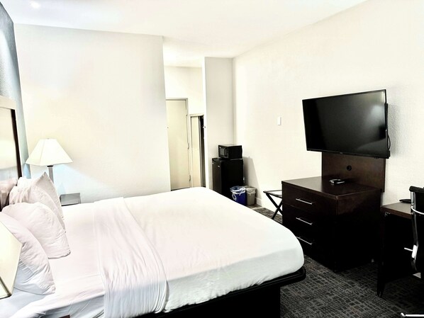 Una habitación de hotel con cama, escritorio, televisor y lámpara.