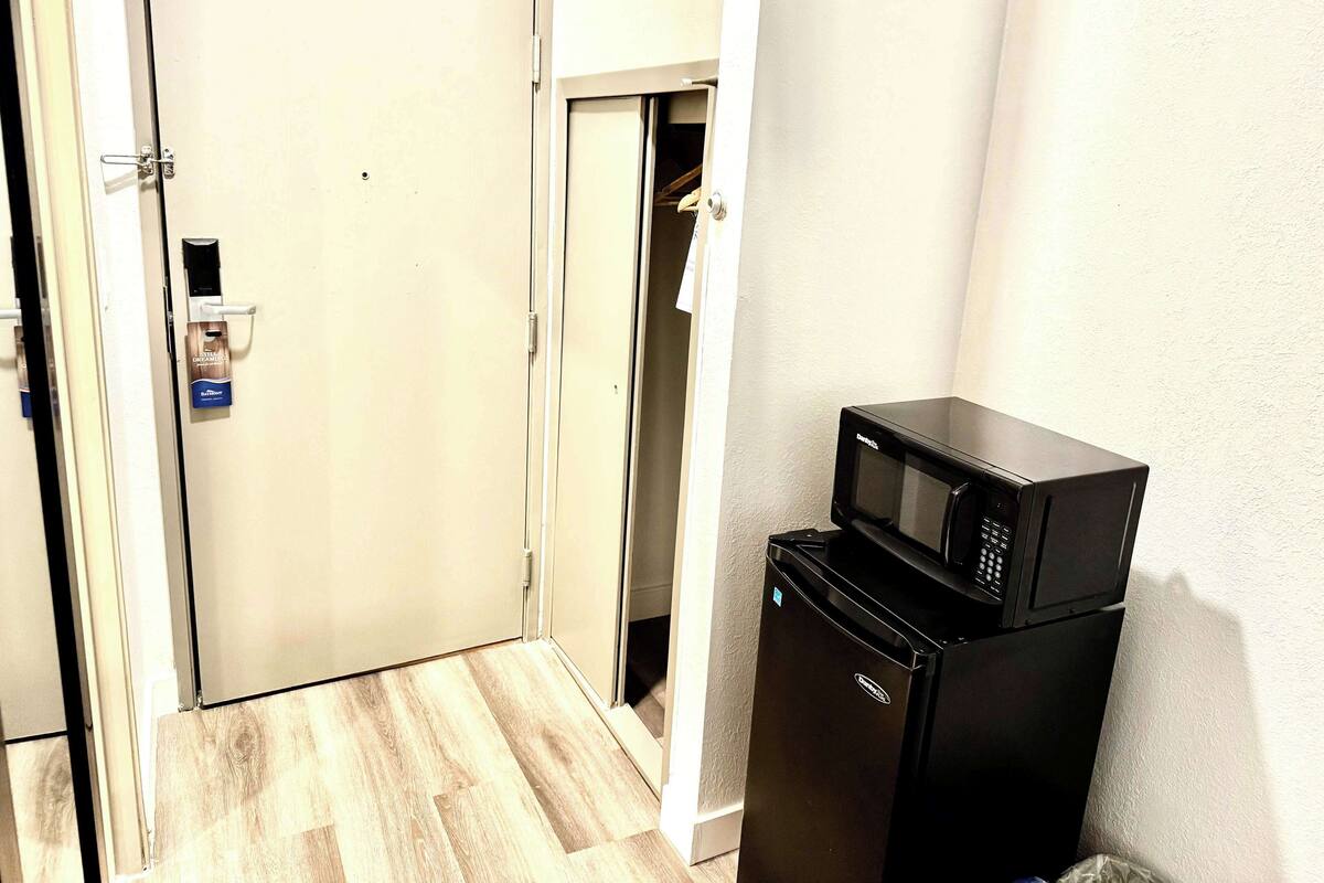 A hotel room with a closed door, a microwave, and a refrigerator.