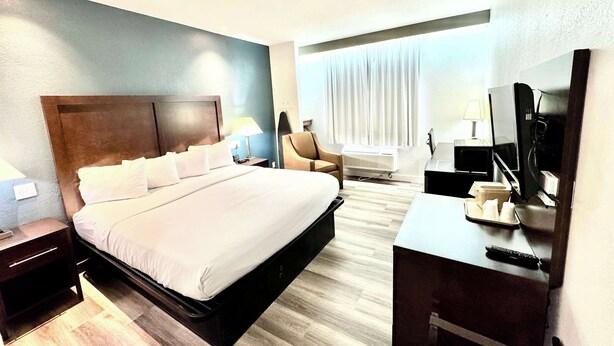 Une chambre d’hôtel avec un grand lit, un bureau avec un ordinateur, une chaise et un téléviseur.