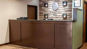 A reception desk with a stone wall backdrop, a logo, and framed certificates.