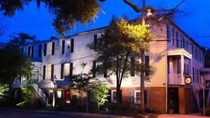 A two-story building with a balcony on the second floor, a porch with a clock, and a tree in front. - 17Hundred90 Inn and Restaurant (Savannah)