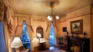 A room with a chandelier, a fireplace, a sofa, a table, and a television. - 17Hundred90 Inn and Restaurant (Savannah)