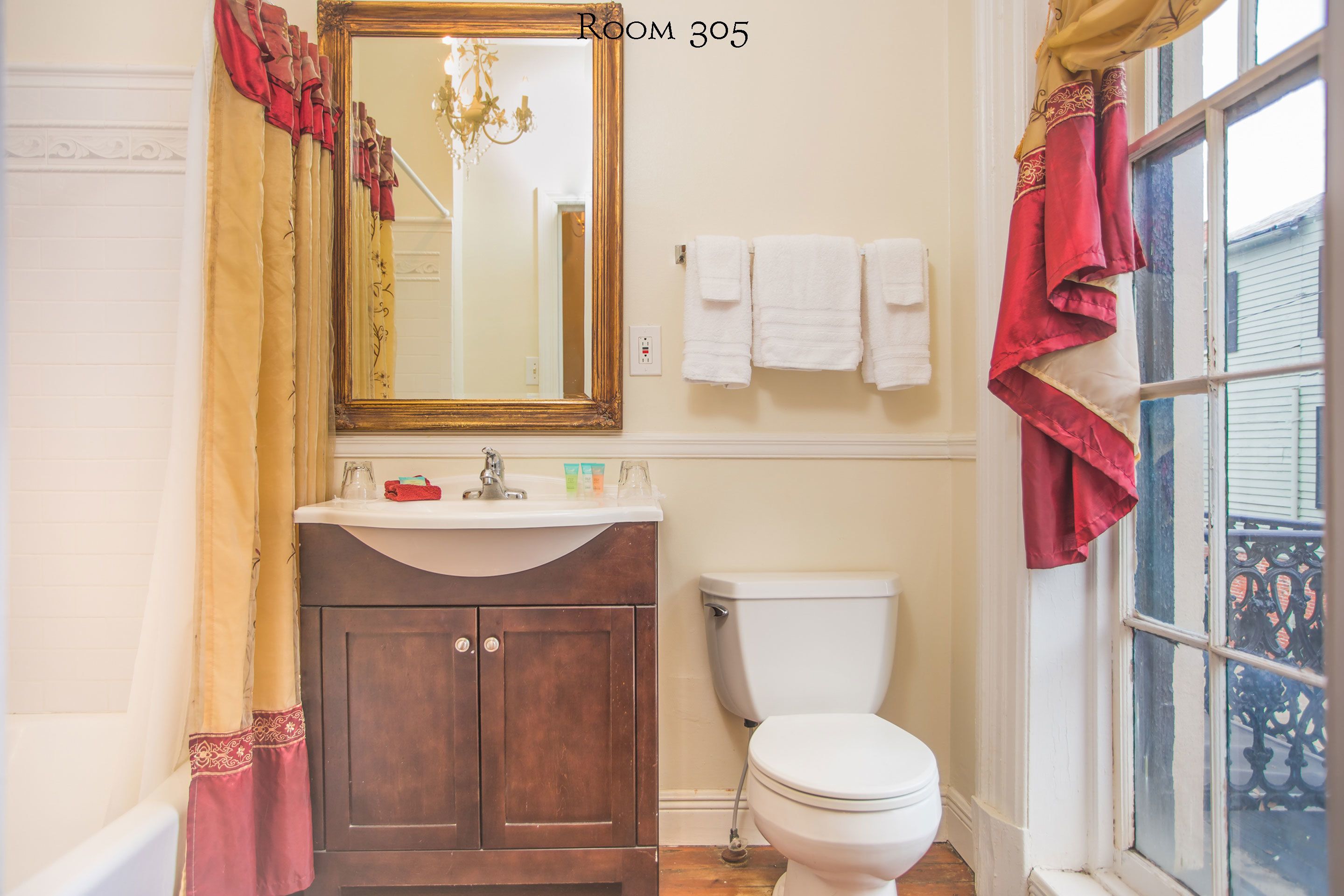 A bathroom with a sink, mirror, toilet, and window with curtains.