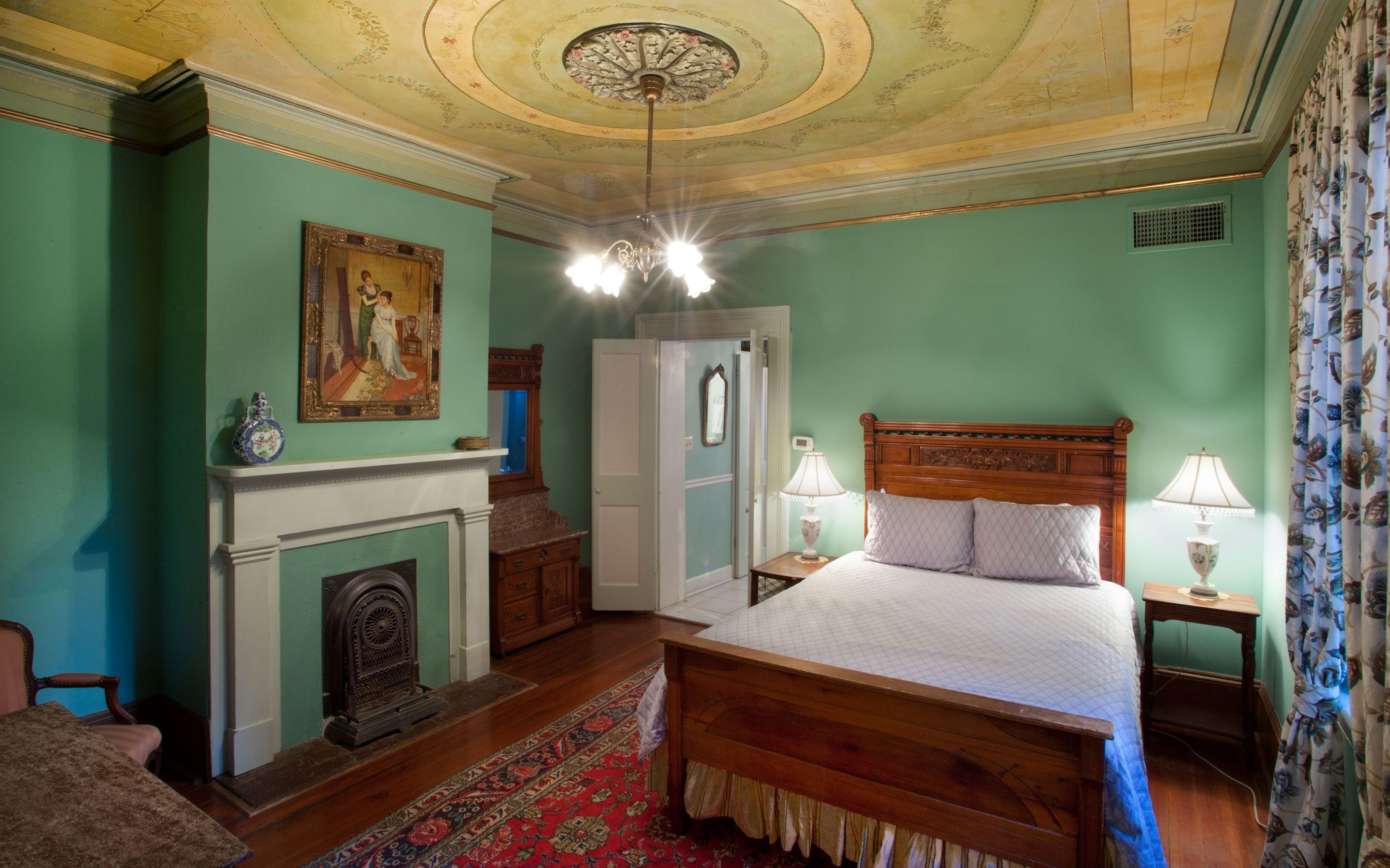 Une chambre à coucher avec un lit en bois, une cheminée, un miroir et un lustre.