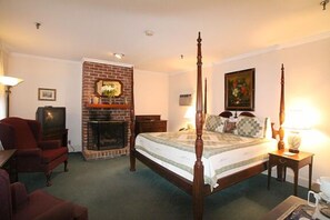 A four-poster bed with a brick fireplace, a television, and a painting on the wall.
