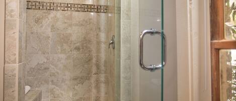 A glass-enclosed shower with a marble tile design and a metal handle.