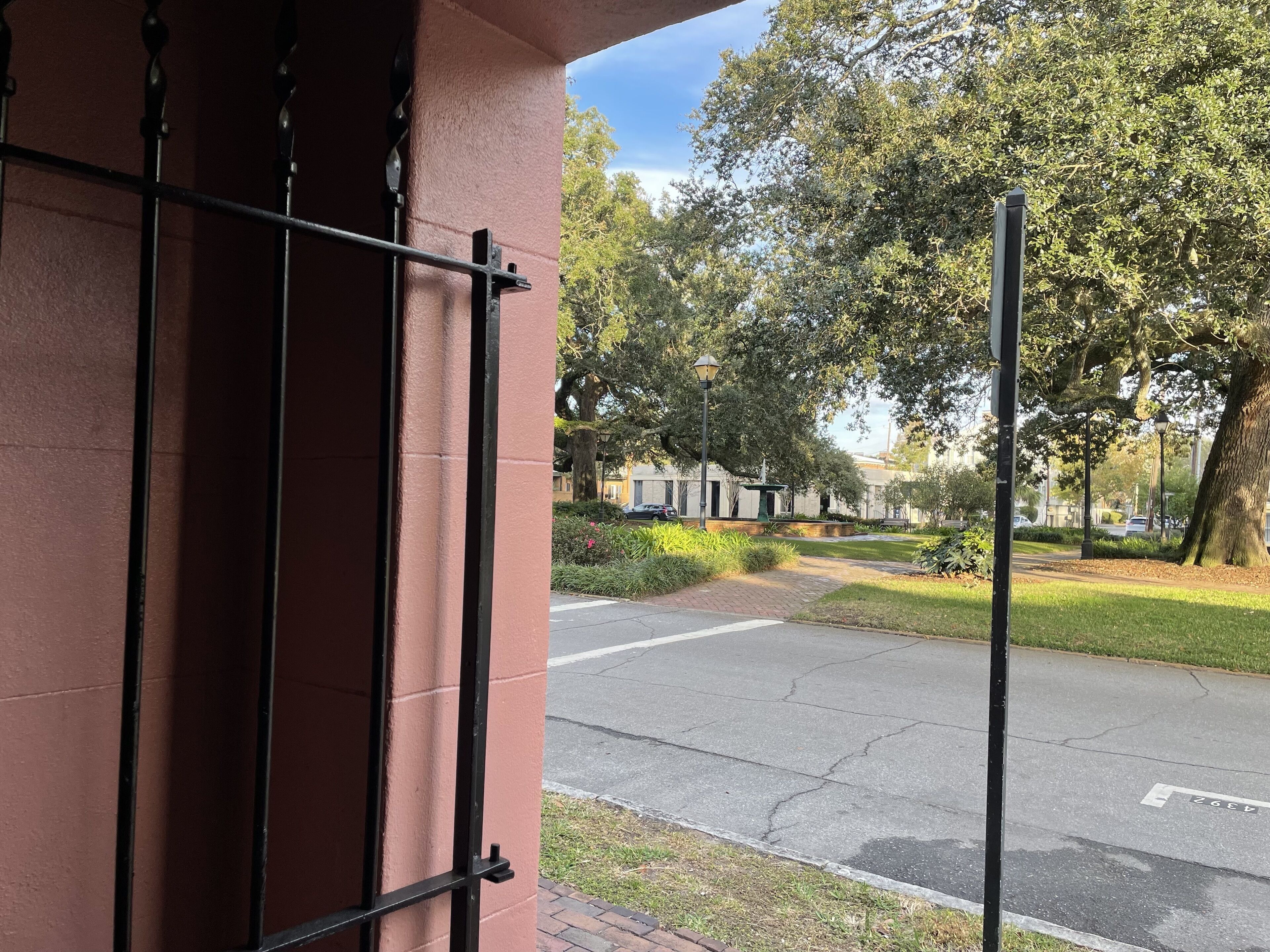 A street view with a red building, a sidewalk, and trees.