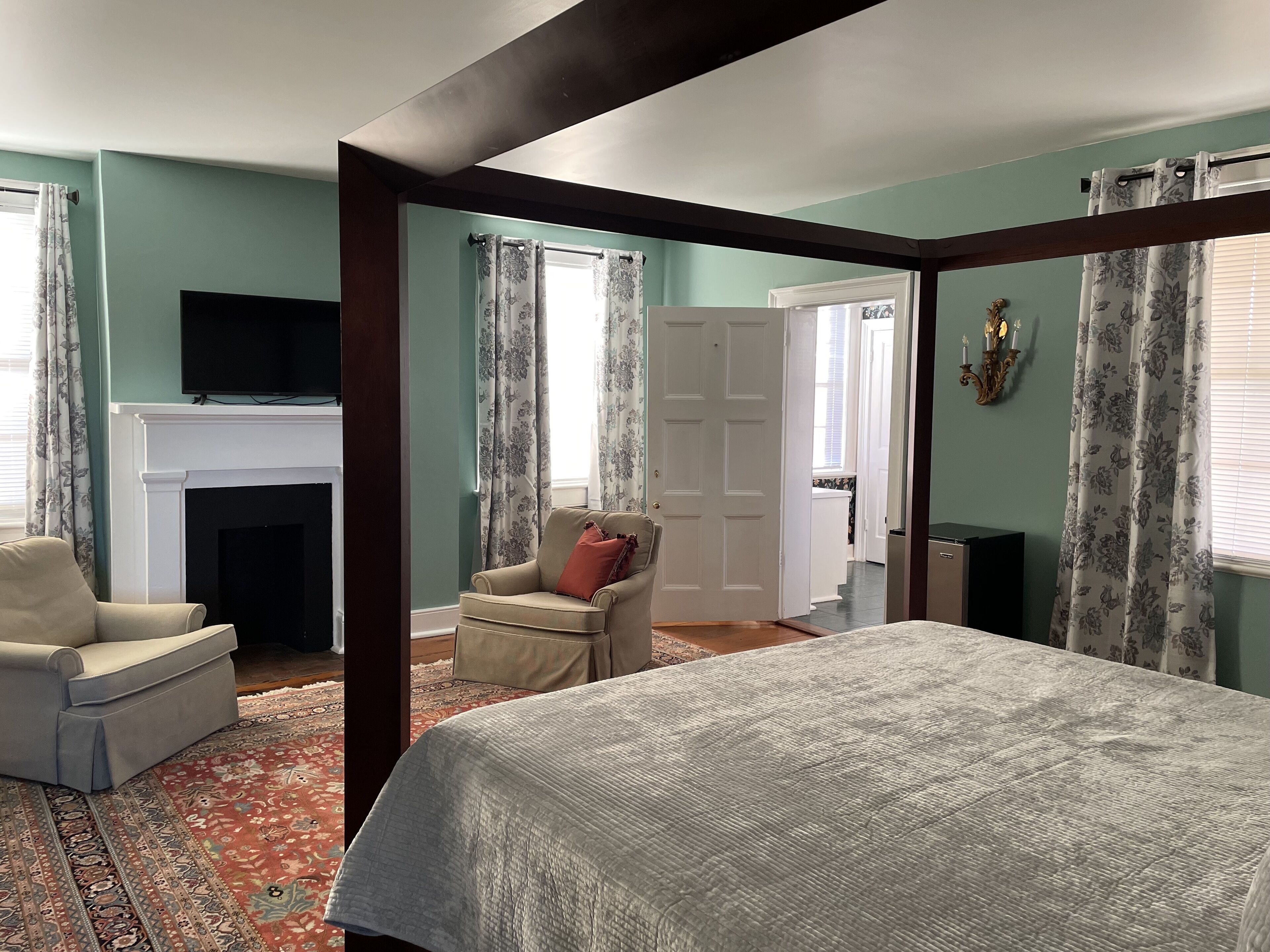 Een kamer met een bed, een open haard, een televisie en een stoel.