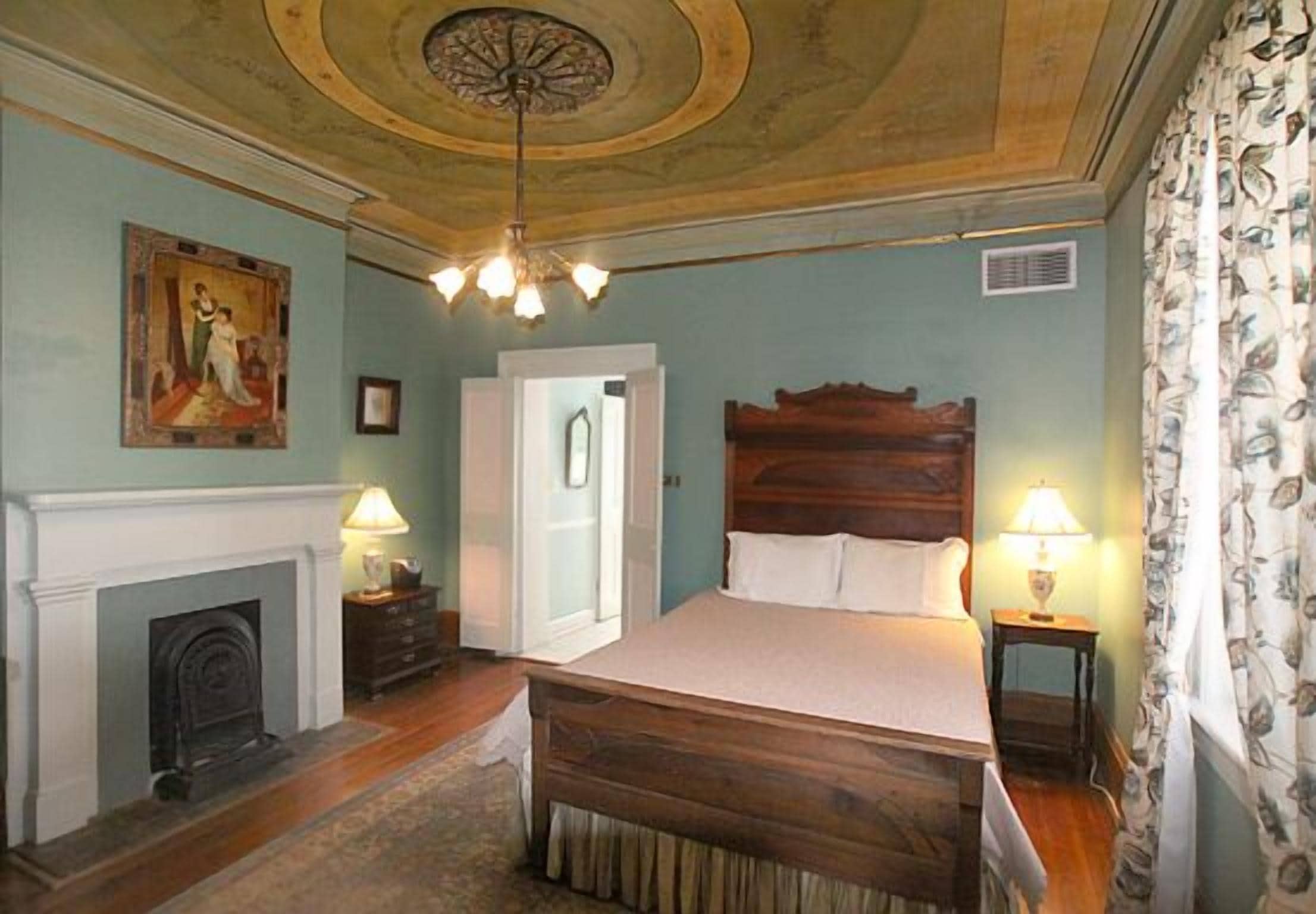 A bedroom with a wooden bed, a fireplace, and a ceiling with a decorative design.