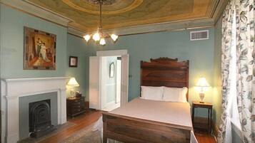 A bedroom with a wooden bed, a fireplace, and a ceiling with a decorative design.