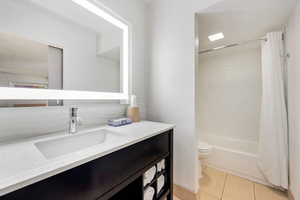 A bathroom with a white sink, mirror, and shower curtain. - The Capitol Hotel Downtown, an Ascend Collection Hotel (Nashville)