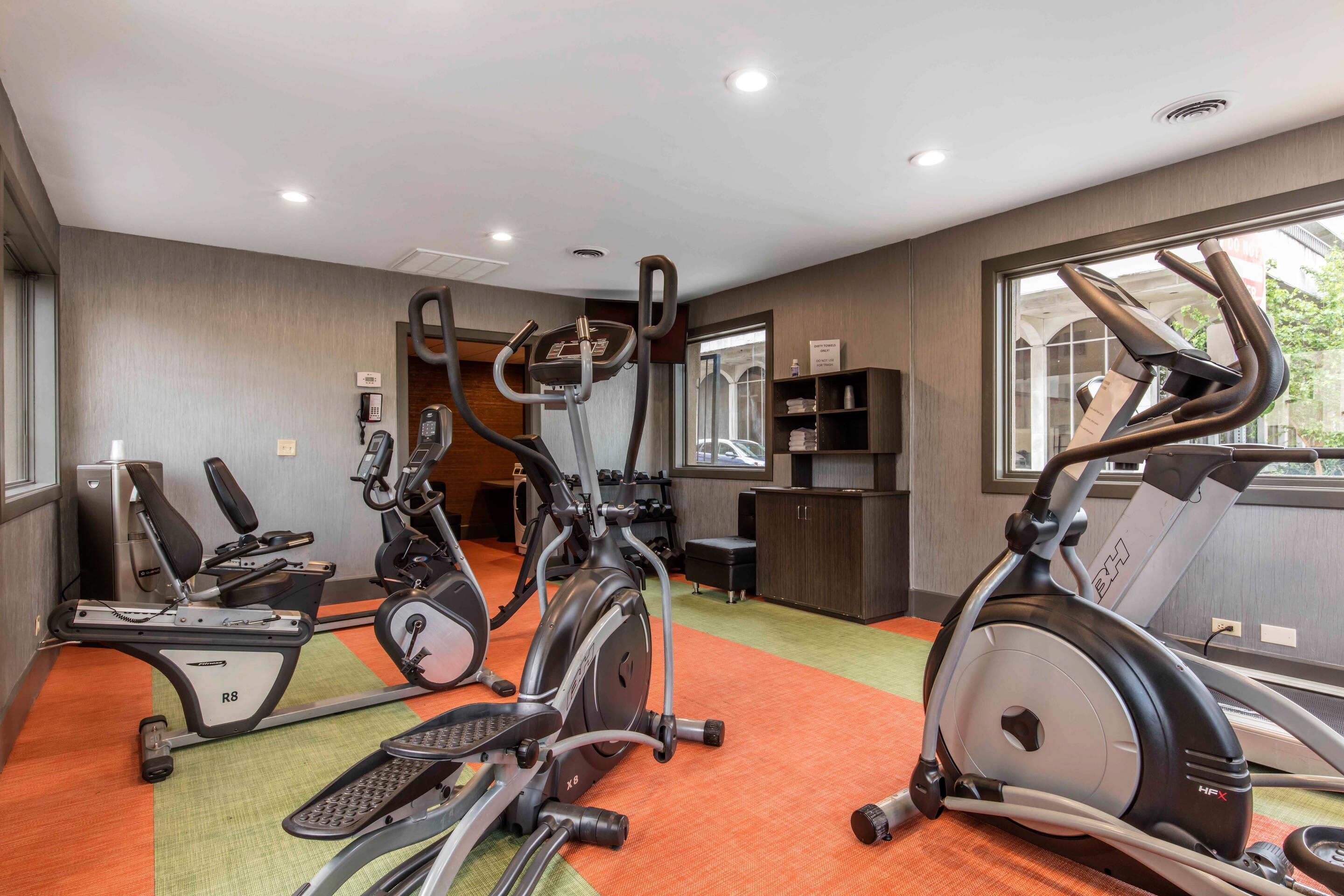 A fitness center with various exercise machines, a reception area, and a view of the outdoors.