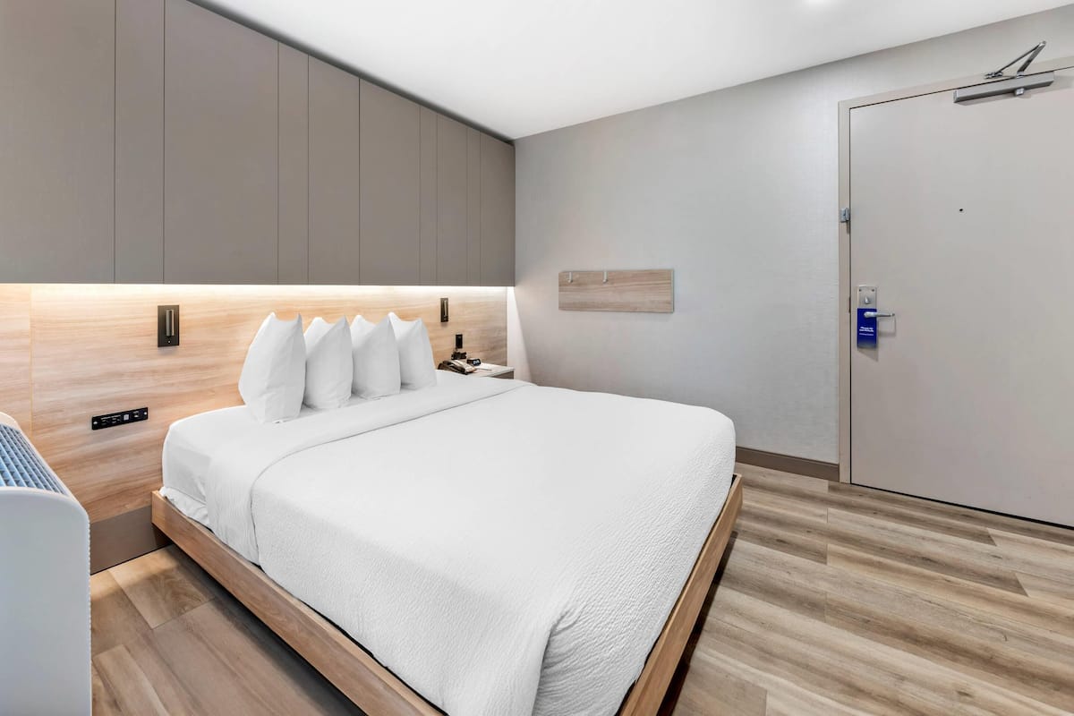 A modern bedroom with a large bed, built-in bedside tables, and a wardrobe.
