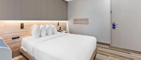 A modern bedroom with a large bed, built-in bedside tables, and a wardrobe.