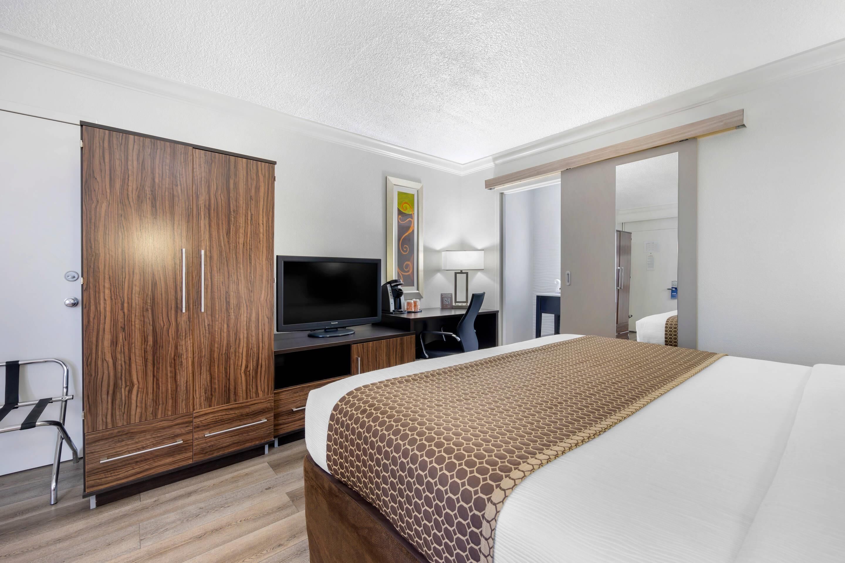 A hotel room with a bed, a TV, a desk, and a wardrobe.