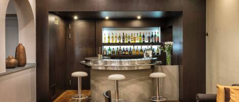 A bar area with a round counter, stools, and a variety of bottles.