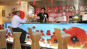 Zona de bar con mostrador, taburetes y una variedad de botellas y vasos.