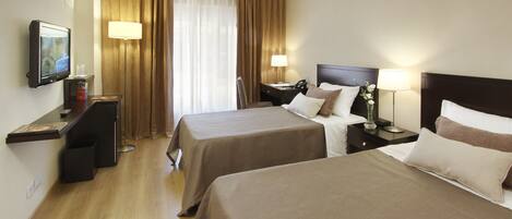 A hotel room with two beds, a desk, a TV, and a window with curtains.