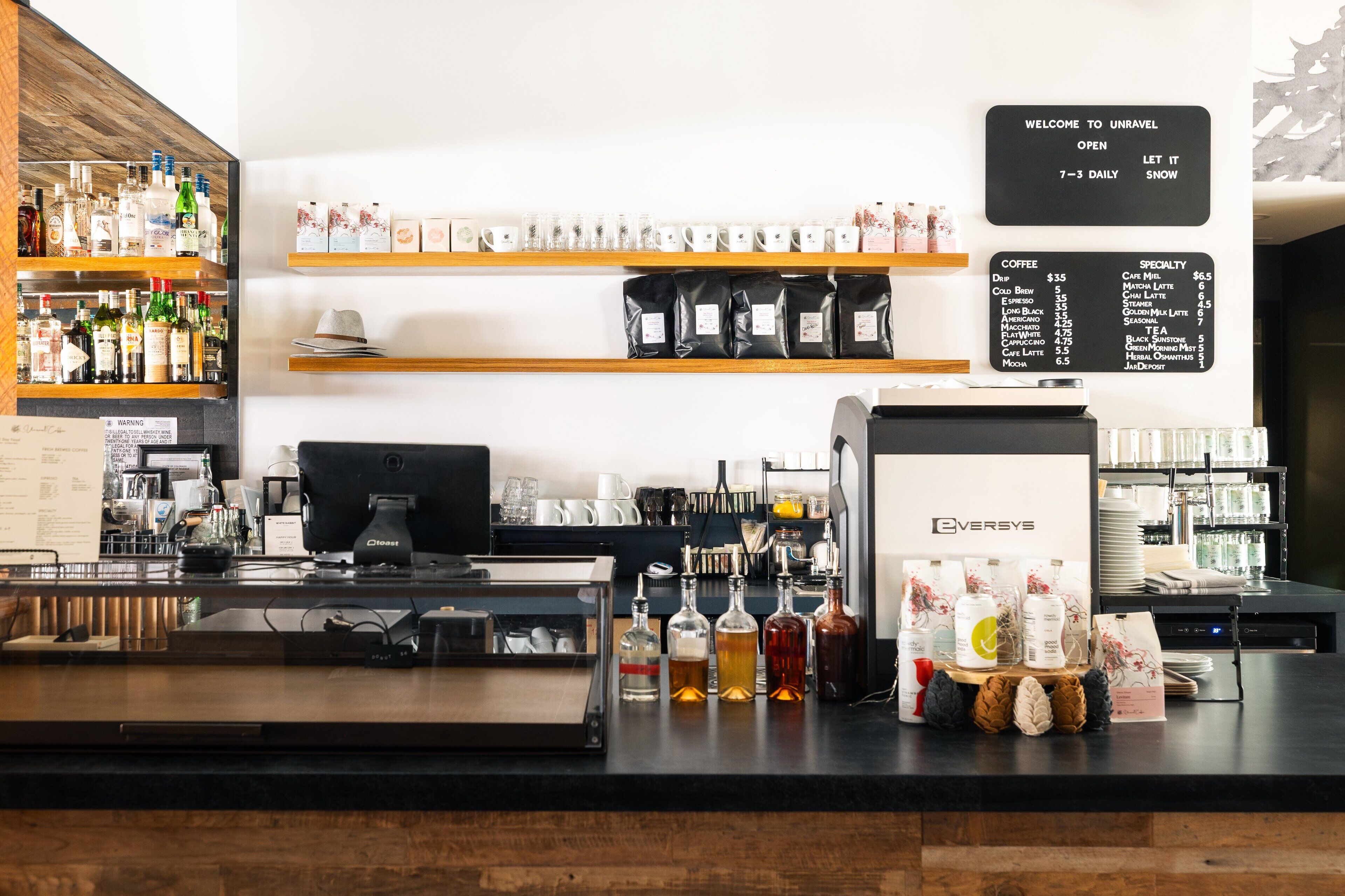 L'intérieur d'un café, avec une machine à café, des étagères remplies de grains de café et un panneau affichant le menu.