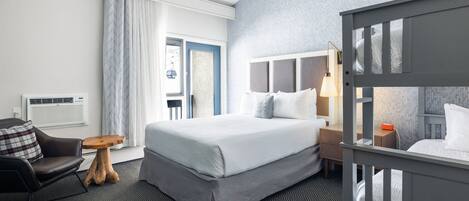 Habitación de hotel con una cama grande, un escritorio, una silla, una mesita de madera y una ventana con cortinas.
