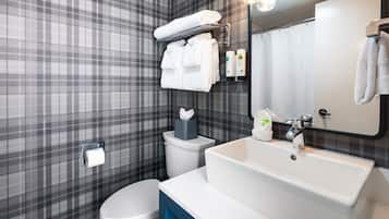 Un baño moderno con un revestimiento de pared estampado en cuadros, un inodoro blanco, un lavabo con espejo y un perchero con toallas dobladas.
