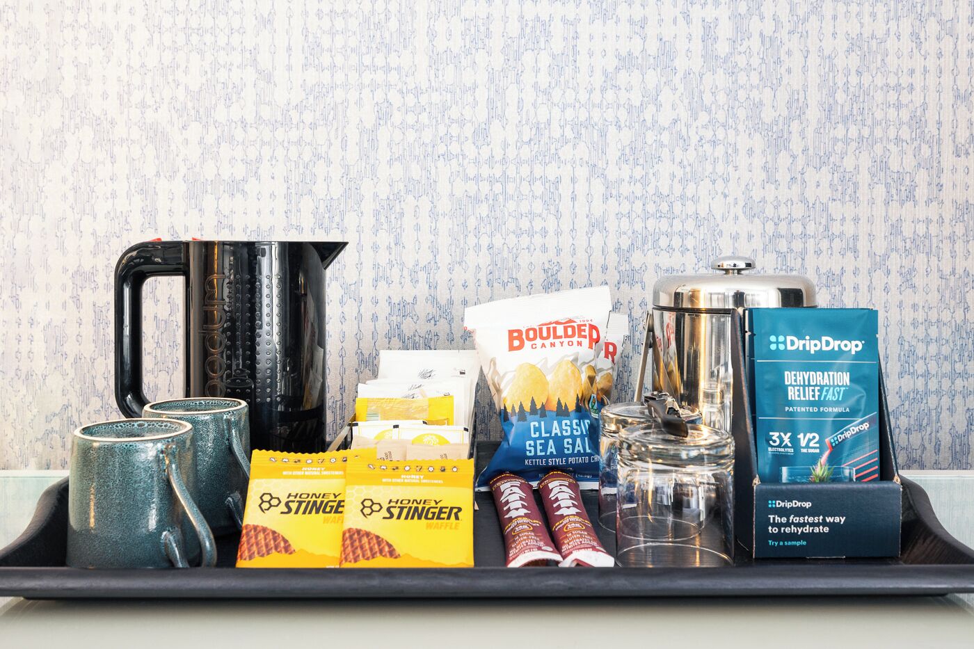 A tray with a kettle, honey stinger waffles, sea salt, and dehydrated snacks.