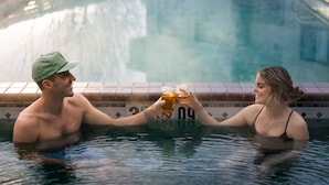 Un couple dans une piscine, chacun tenant un verre à la main.