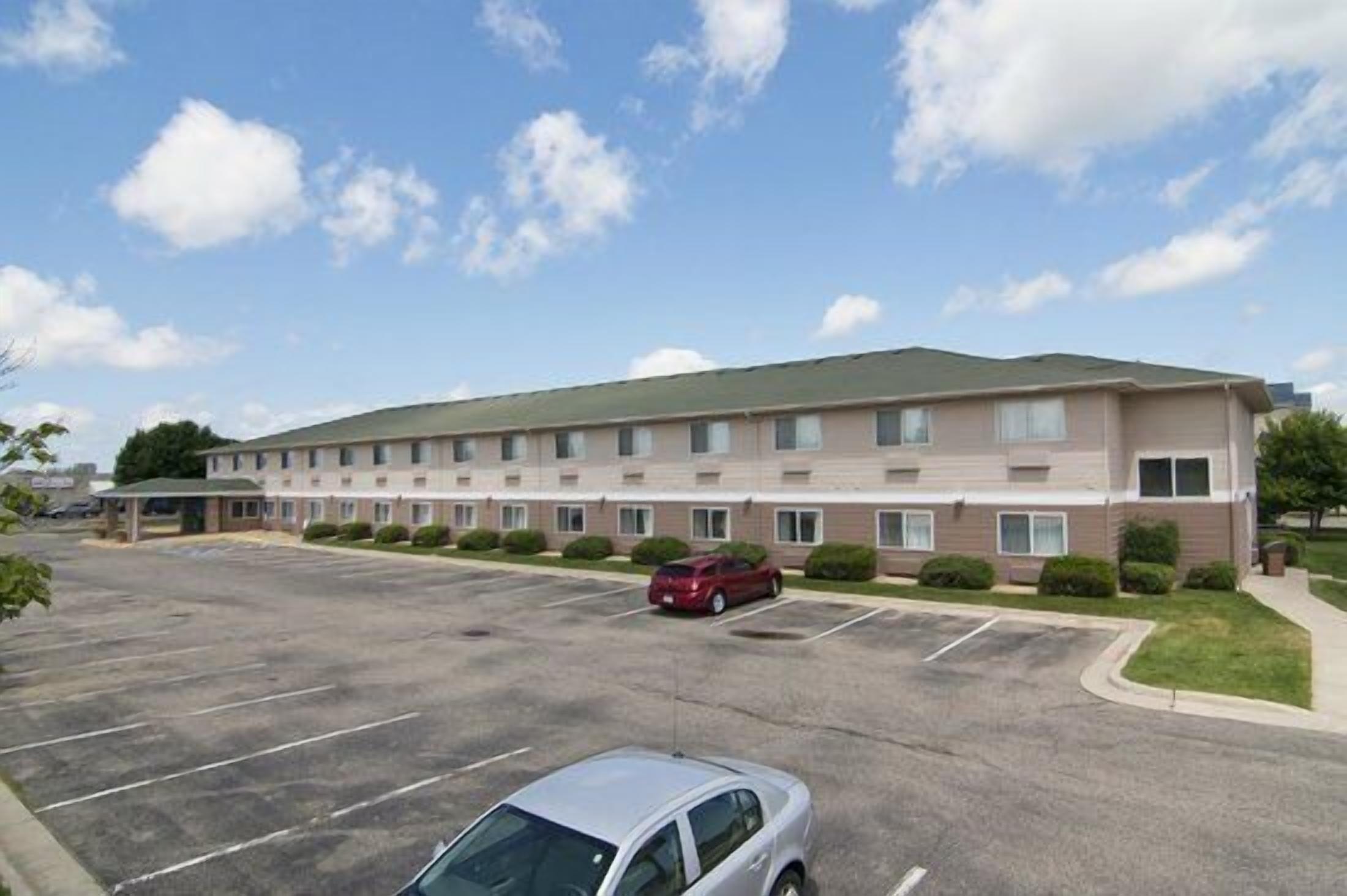 A multi-story hotel with a parking lot in front.
