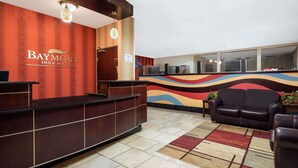 A reception area with a Baymont Inn & Suites sign, a reception desk, a sofa, and a patterned rug. - Quality Inn & Suites Mankato East (Mankato)