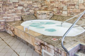 A stone-walled hot tub with a metal ladder, surrounded by tiled flooring and a 'No Smoking' sign.