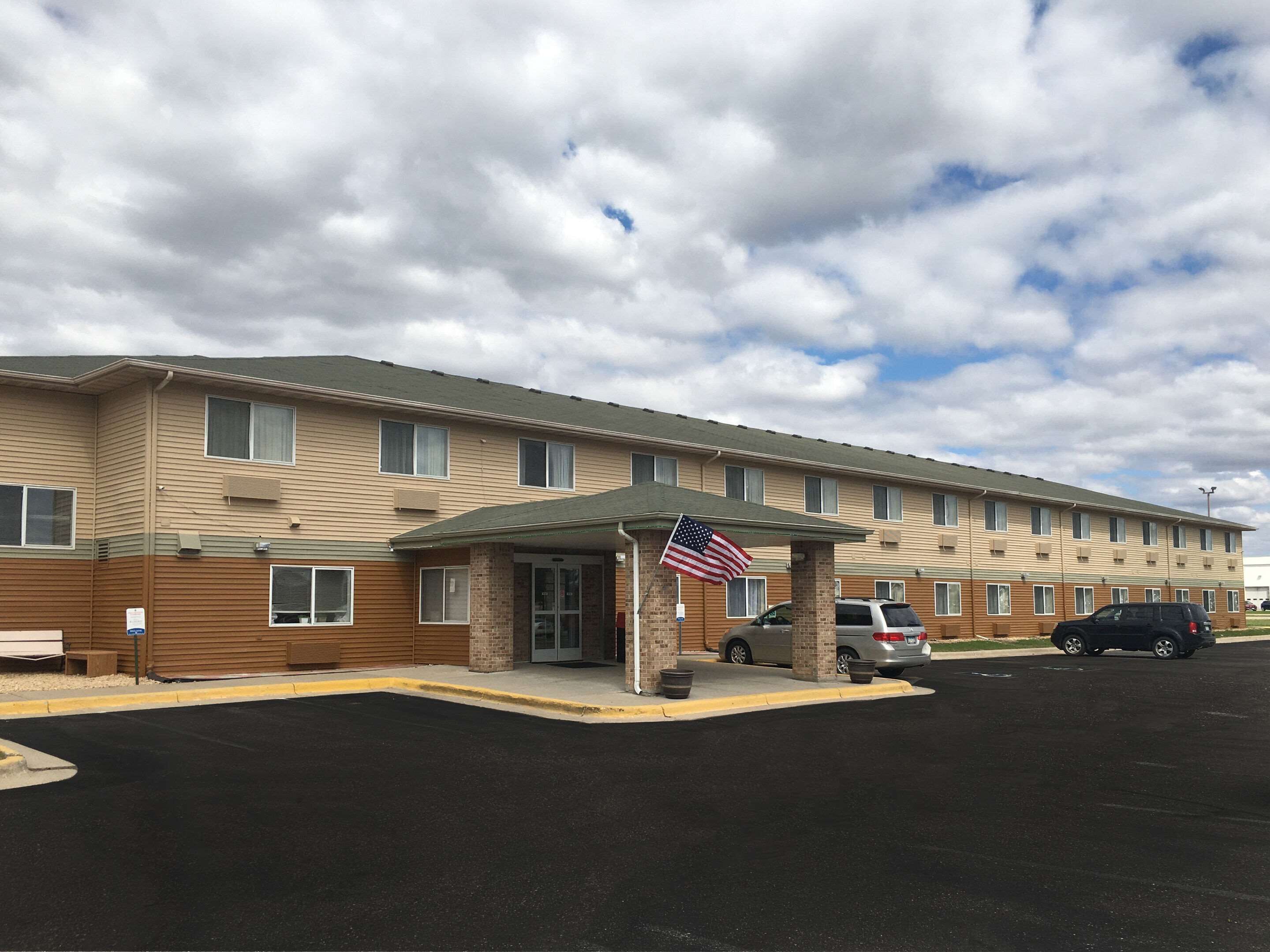 Un motel de varios pisos con un acceso cubierto y una bandera estadounidense.