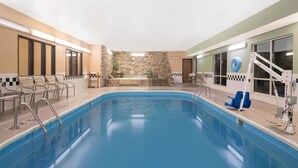 An indoor swimming pool with a stone wall, seating area, and a lifeguard stand. - Quality Inn & Suites Mankato East (Mankato)